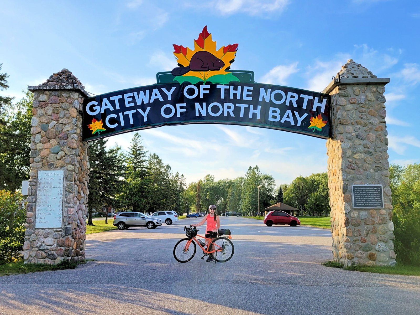 The stone Gateway of the North arch welcoming visitors to the City of North Bay, with a cyclist standing beneath it